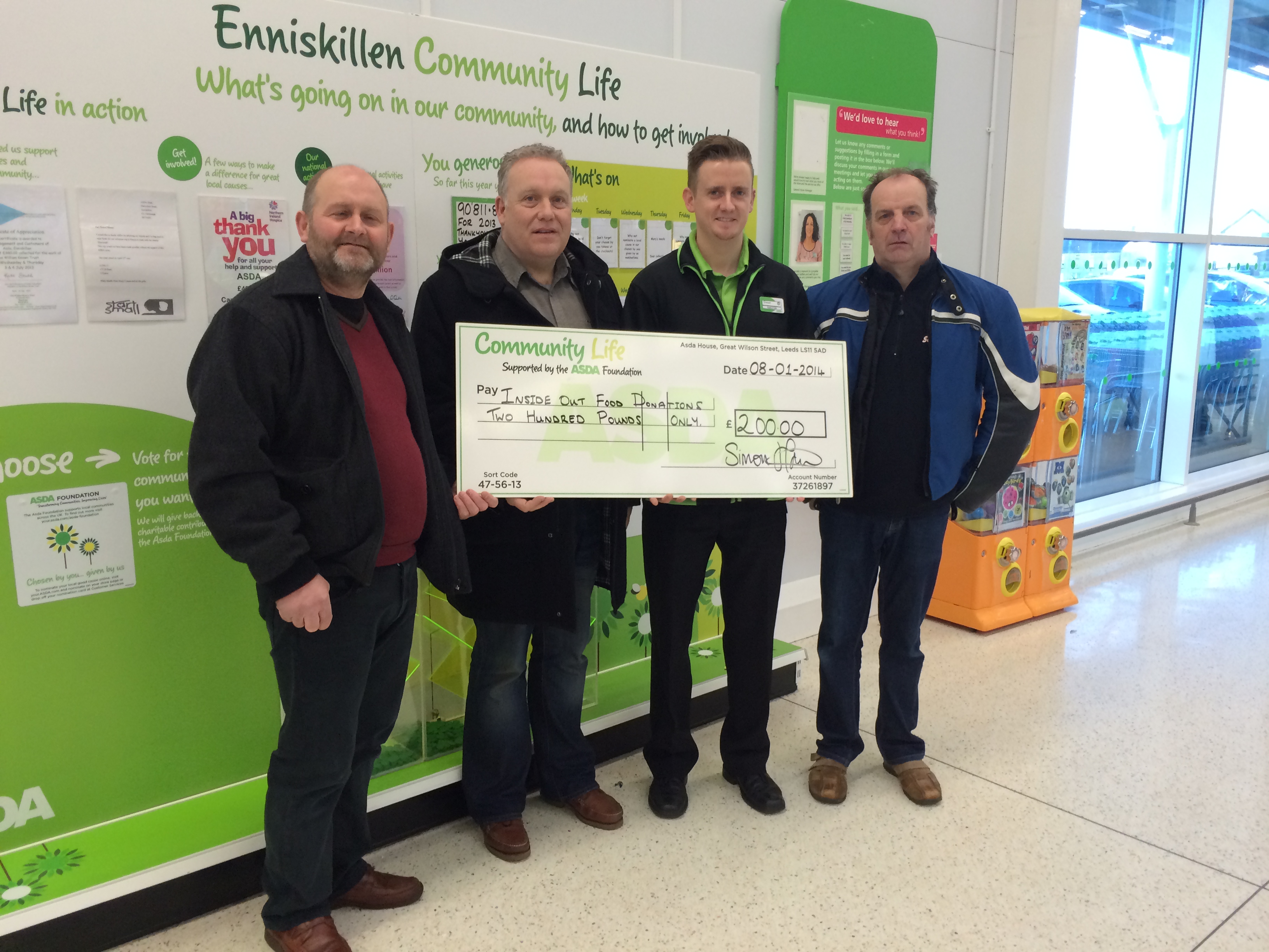 John, Willie, and Keith being presented with a cheque from Simon, Community Life Champion, at Asda Enniskillen